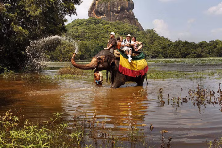 Một chú voi chở du khách và tinh nghịch phun nước ở Sigiriya, cách thủ đô Colombo của Sri Lanka 100 km về phía tây bắc. Ảnh: ap.
