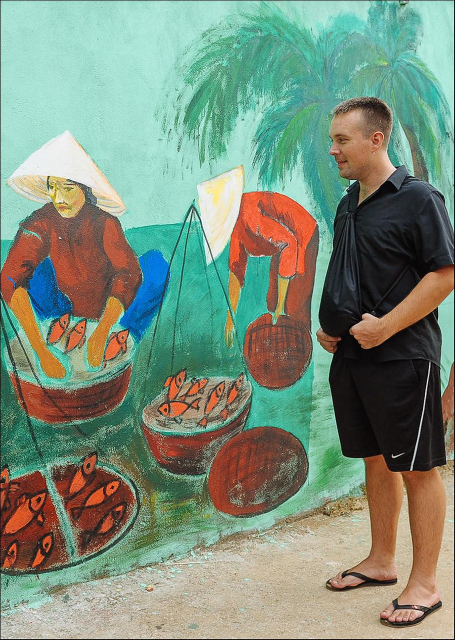 Một du khách nước ngoài thích thú ngắm nhìn bức tranh hàng cá đầy giản dị, mang đậm chất làng quê. Hầu hết bích họa là những hình ảnh gắn liền với cuộc sống đời thường của người dân chài, khắc họa nhịp sống miền biển một cách chân thực nhất. Đây cũng là cách quảng bá hình ảnh đất nước nhẹ nhàng mà sâu sắc. Ảnh: Hai Hoang.