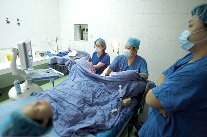 Thứ trưởng Bộ Y tế kiêm giám đốc Trung tâm Hỗ trợ sinh sản quốc gia Nguyễn Viết Tiến (giữa) thao tác trong một ca phẫu thuật - Ảnh: Nguyễn Khánh