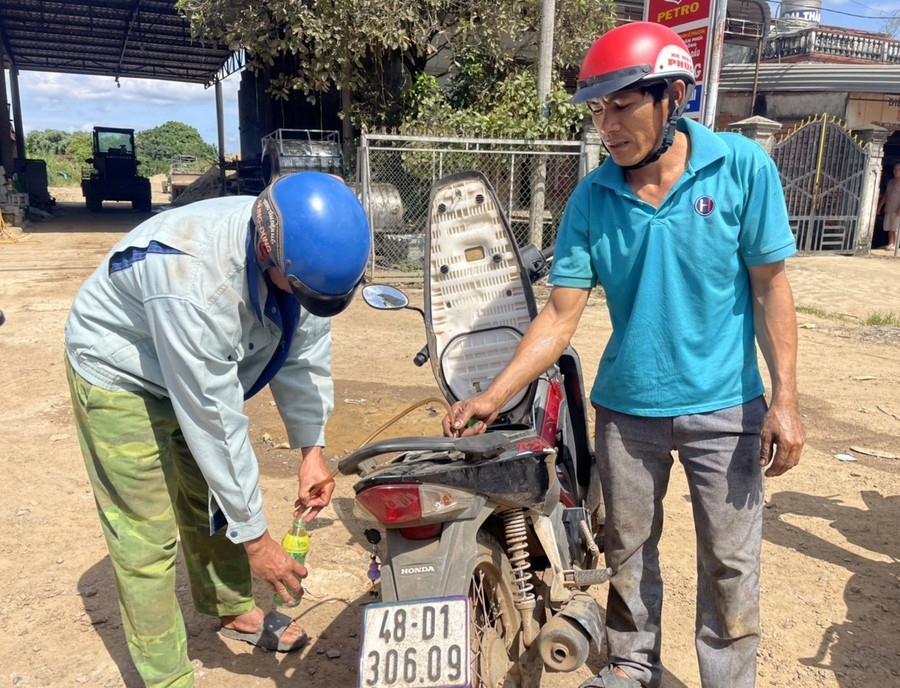 Khi cây xăng hết hàng, không có để bán thì anh Ửng phải mượn vòi nhựa, xin xăng từ người đi đường để tìm đến cây xăng. Ảnh: Phan Tuấn