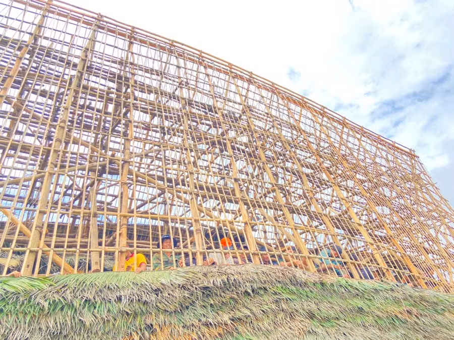 Thanh niên dồn sức lợp mái nhà rông. Ảnh: HT