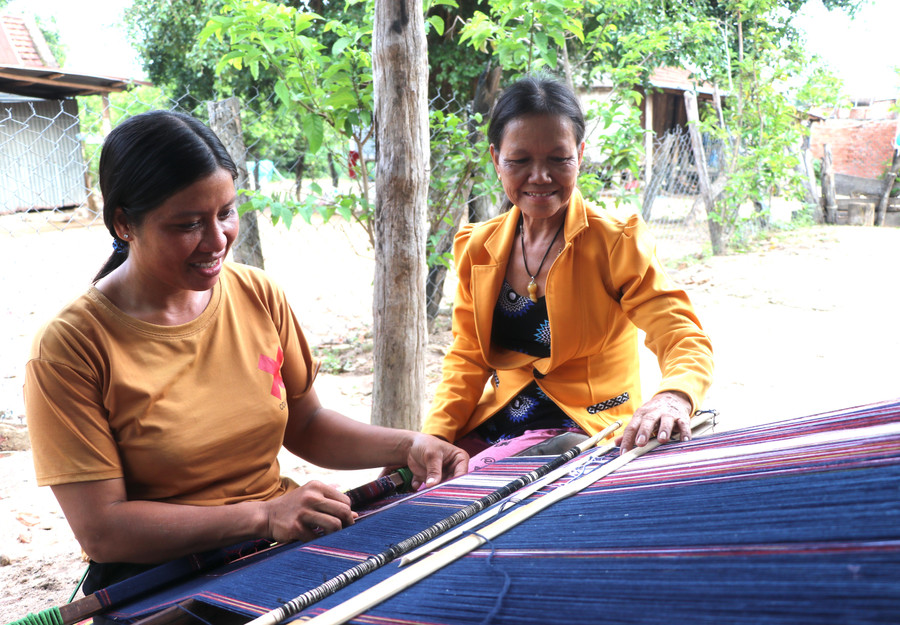 Bà Đinh Thị Drinh (bìa phải, tổ dân phố Plei Nghe, thị trấn Kông Chro, huyện Kông Chro) hướng dẫn thành viên tổ dệt thổ cẩm thêu dệt họa tiết, hoa văn khó. Ảnh: An Phát
