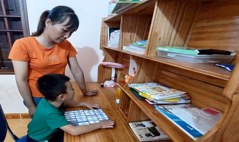 Chị Phùng Thị Ngọc dạy con học bài. Ảnh: Vĩnh Hoàng