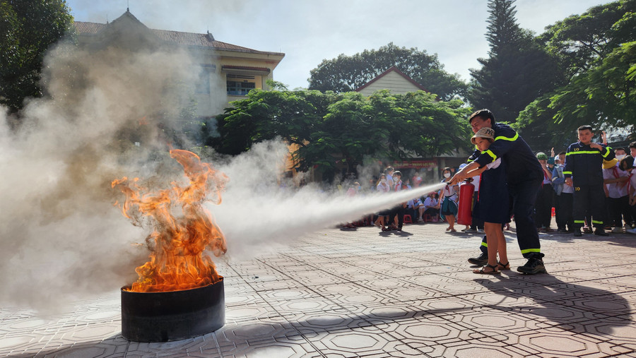 Các em học sinh Trường Tiểu học Chu Văn An (phường Tây Sơn, TP. Pleiku) được thực hành dập tắt đám cháy bằng bình cứu hỏa. Ảnh: Phan Lài