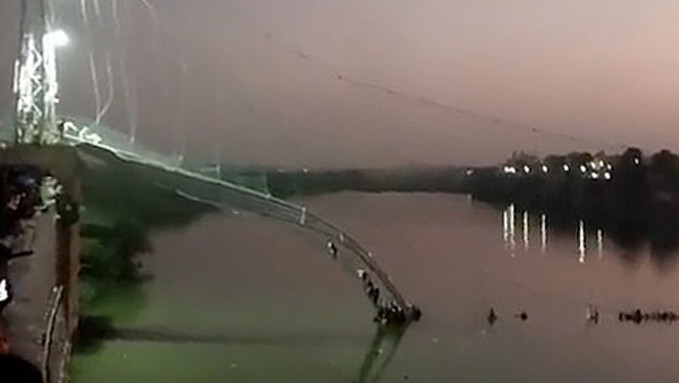 Cây cầu cáp treo bị sập khi có vài trăm người đi bên trên qua đoạn sông Machhu ở Morbi, Gujarat, Ấn Độ chiều tối 30-10. Ảnh: Twitter Cây cầu cáp treo bị sập khi có vài trăm người đi bên trên qua đoạn sông Machhu ở Morbi, Gujarat, Ấn Độ chiều tối 30/10. Ảnh: Twitter