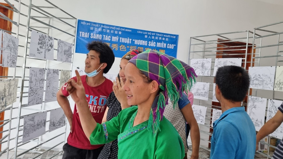 Xeng Thị Chúm, người dân tộc Tày ở xã Túng Sán, đang xem các tác phẩm ký họa về quê hương mình