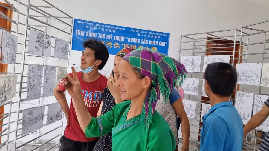 Xeng Thị Chúm, người dân tộc Tày ở xã Túng Sán, đang xem các tác phẩm ký họa về quê hương mình