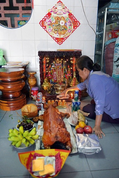 Một phụ nữ sống ở Phnom Penh, Campuchia, chuẩn bị lễ vật gồm heo quay, hoa quả để cúng tổ tiên trong ngày 18-2.