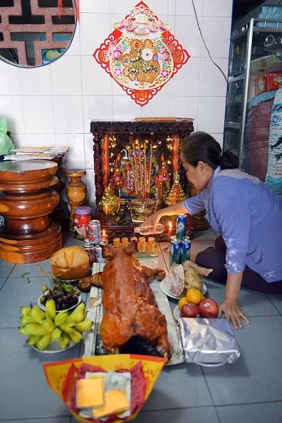 Một phụ nữ sống ở Phnom Penh, Campuchia, chuẩn bị lễ vật gồm heo quay, hoa quả để cúng tổ tiên trong ngày 18-2.