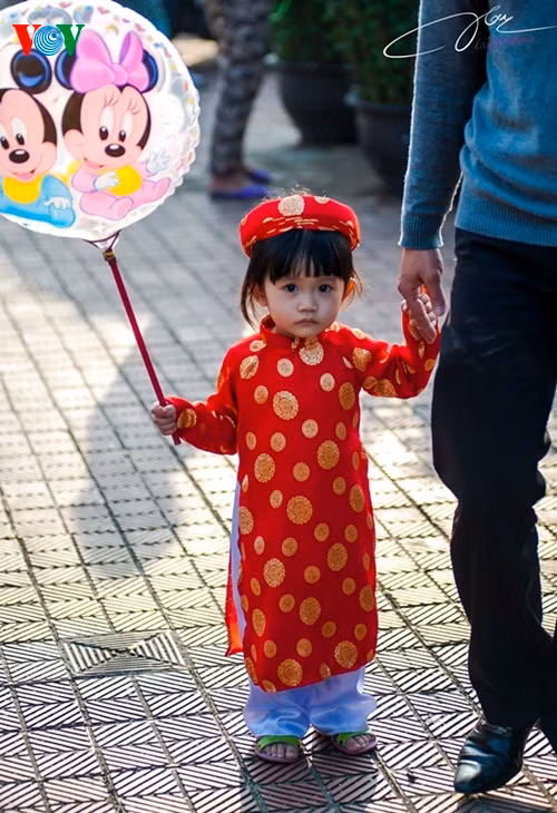 Em bé đi xem chợ hoa trong áo dài truyền thống.