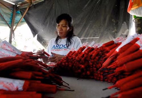 Một nữ công nhân đang quấn pháo ở phía bắc Manila, Philippines.