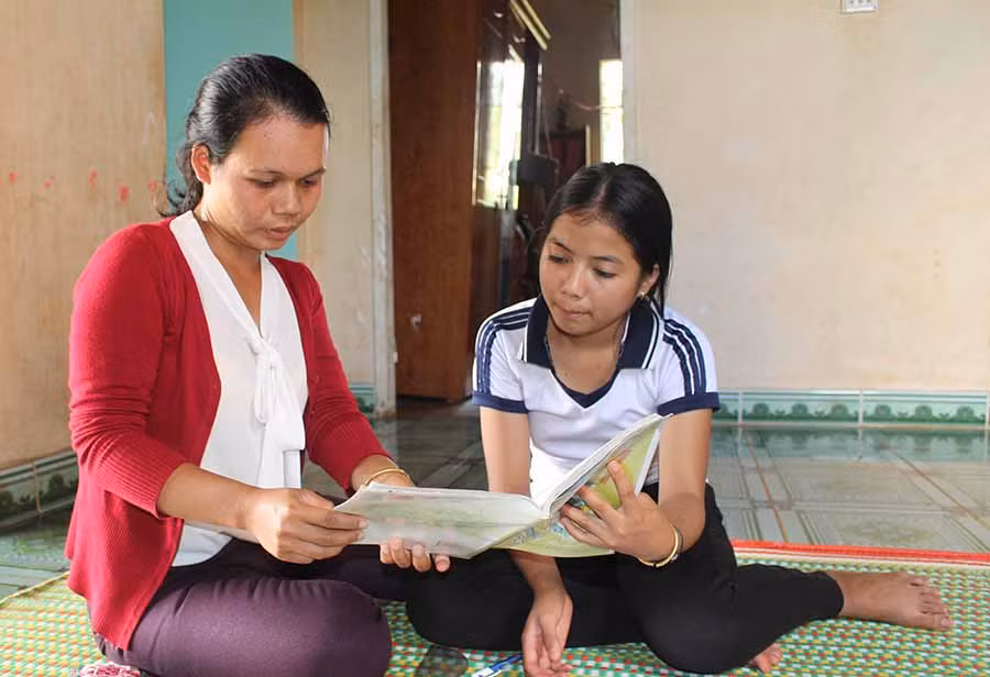  Chị Ksor Linh hướng dẫn bài tập về nhà cho em HYim-một cô bé rất ham học của làng Nhing. Ảnh: N.G