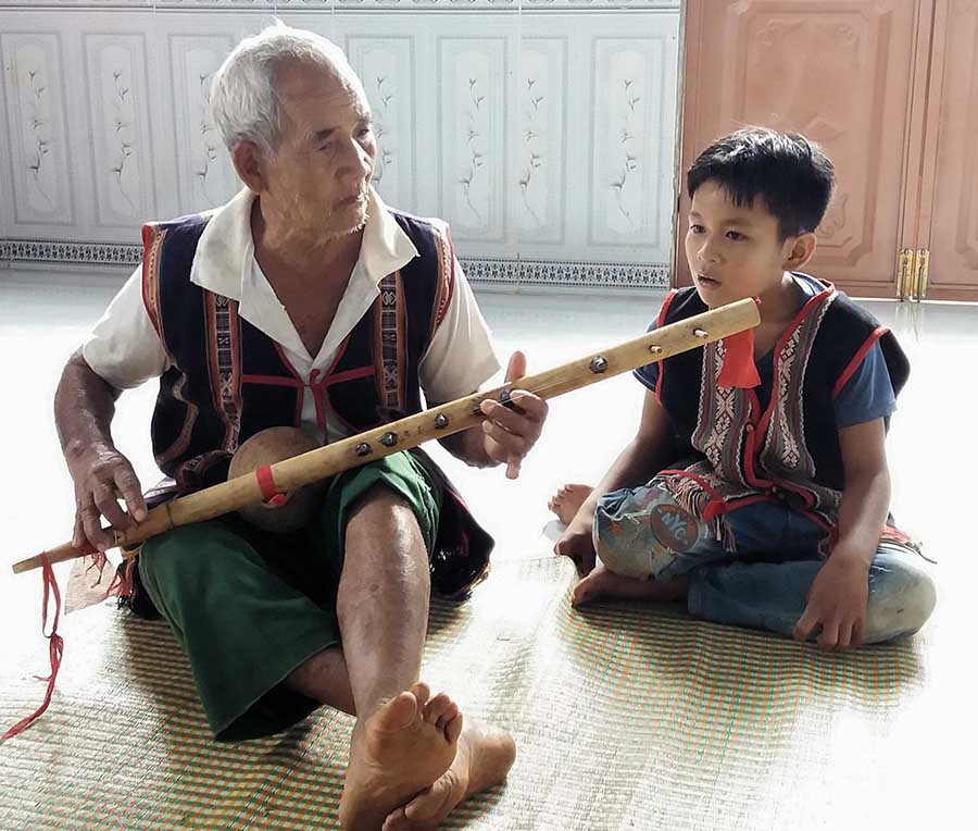  Già Rơ Châm Nha đàn cho cháu Tứ hát. Ảnh: N.N