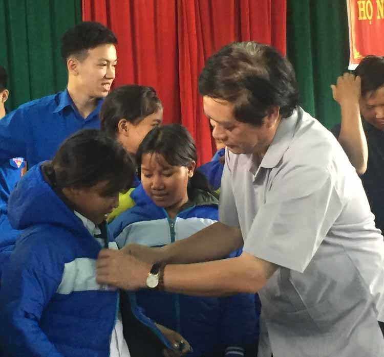 Giám đốc sở Tài chính Nguyễn Dũng mặc áo ấm cho các cháu học sinh. Ảnh: Phương Loan