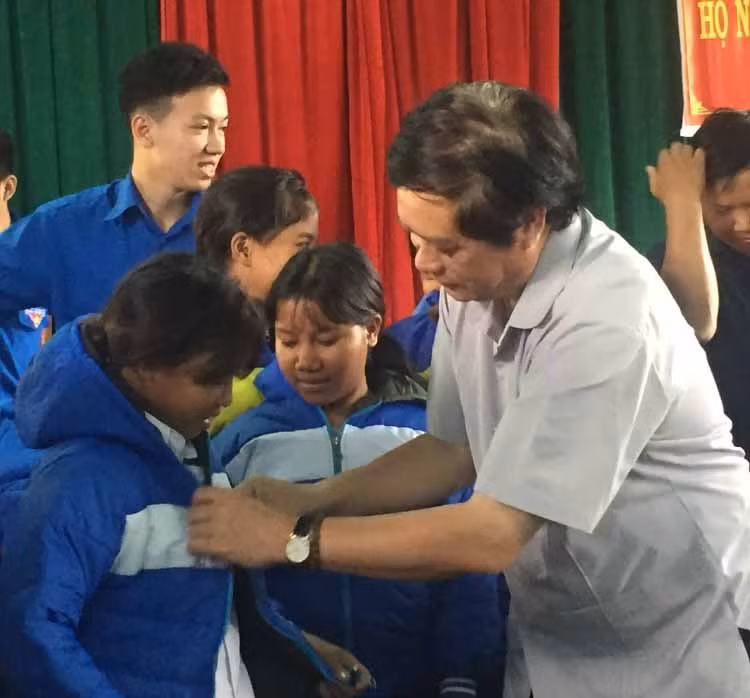 Giám đốc sở Tài chính Nguyễn Dũng mặc áo ấm cho các cháu học sinh. Ảnh: Phương Loan