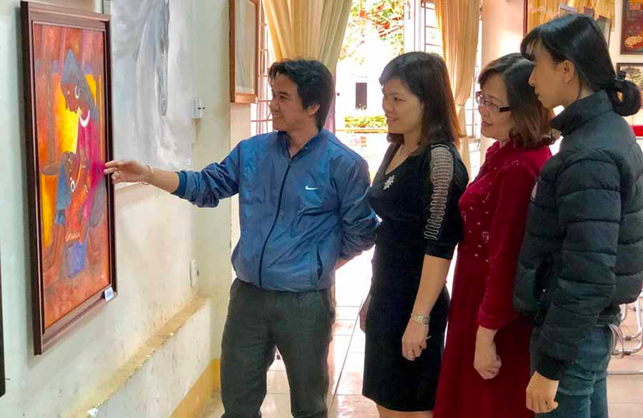  Họa sĩ Nguyễn Văn Chung (ngoài cùng bên trái) giới thiệu tranh cho người xem. Ảnh: T.B