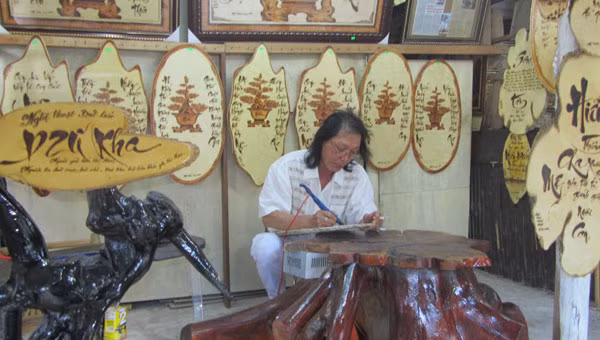 Nghệ nhân Dzũ Kha viết thơ bằng bút lửa. Ảnh: N.N.P