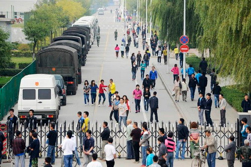 Công nhân nhà máy Foxconn tại thành phố Thái Nguyên, tỉnh Sơn Tây, Trung Quốc đi ngang qua xe cảnh sát chống bạo động tại lối ra vào nhà máy hôm 24-9.