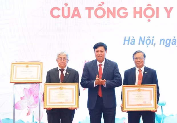 Thứ trưởng Bộ Y tế Đỗ Xuân Tuyên trao Bằng khen của Thủ tướng Chính phủ cho 2 cá nhân của Tổng hội Y học Việt Nam. (Ảnh: Văn Điệp/TTXVN)