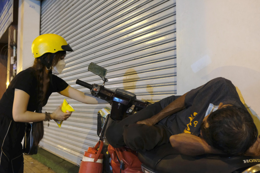 Chị Mai Thị Diệu Hiền (thành viên của nhóm thiện nguyện Đêm Sài Gòn) phát quà cho người vô gia cư. Ảnh: Đào Nguyên Chị Mai Thị Diệu Hiền (thành viên của nhóm thiện nguyện Đêm Sài Gòn) phát quà cho người vô gia cư