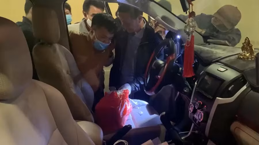 Nguyễn Mỹ (bên trái) bị khống chế cùng tang vật gói hàng bọc bao ni lông màu đỏ. Ảnh: Nguyễn Tú 