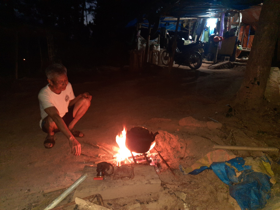 Ông Phượng nấu nước bằng củi ở giữa rừng. Ảnh: Kỳ Phú