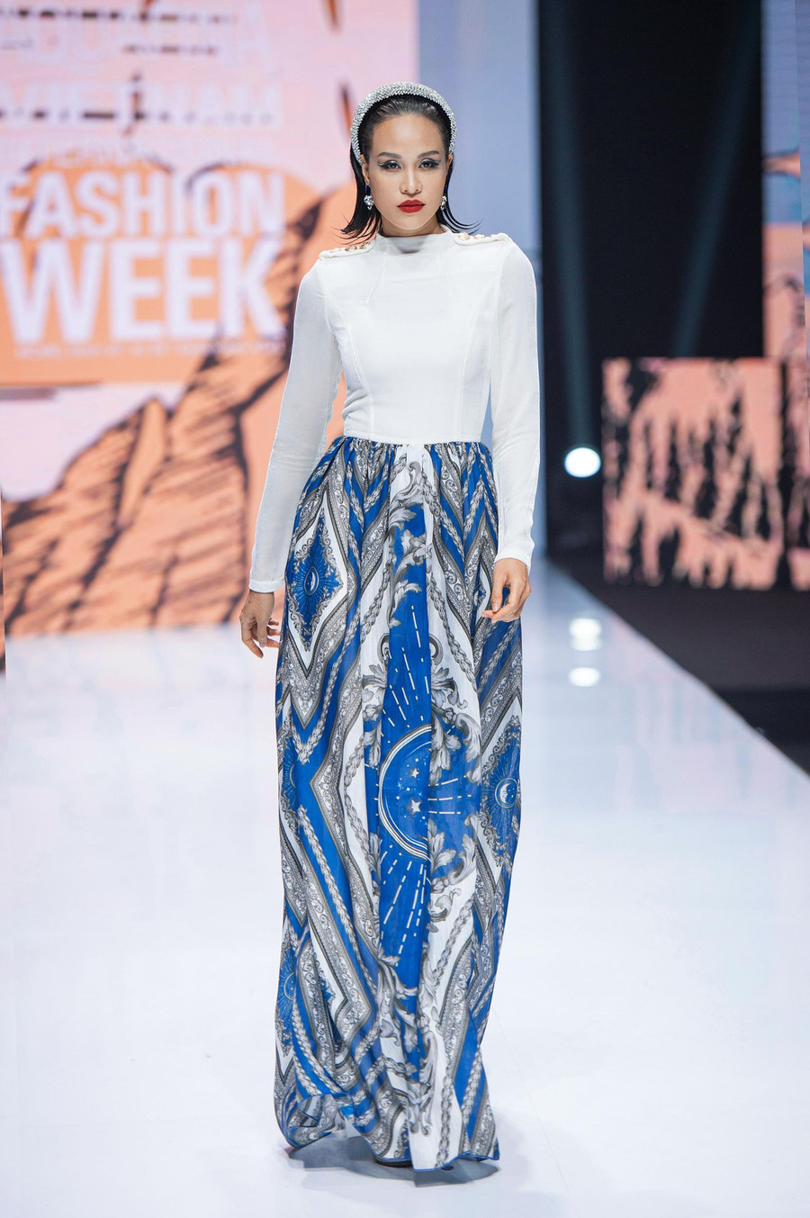 Siêu mẫu Phương Mai kết thúc BST với vẻ đẹp rạng rỡ, đầy quyến rũ trong thiết kế đầm dạ hội với thân trên là nhung the trắng toả sáng cùng tùng váy được in họa tiết mặt trăng tinh xảo với những sọc dài cách điệu tỏa sáng trên thân váy.