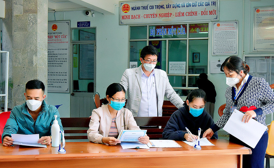 Cán bộ Chi cục Thuế TP. Pleiku hướng dẫn người dân làm thủ tục khai thuế. Ảnh: Đức Thụy