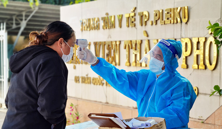 Nhân viên y tế kiểm tra thân nhiệt người dân trước khi vào Bệnh viện thành phố Pleiku - Ảnh Bá Bính