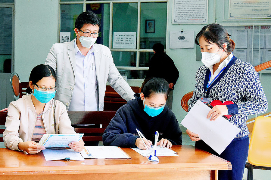  Cán bộ Chi cục Thuế TP. Pleiku hướng dẫn hộ kinh doanh kê khai thuế. Ảnh: Đức Thụy