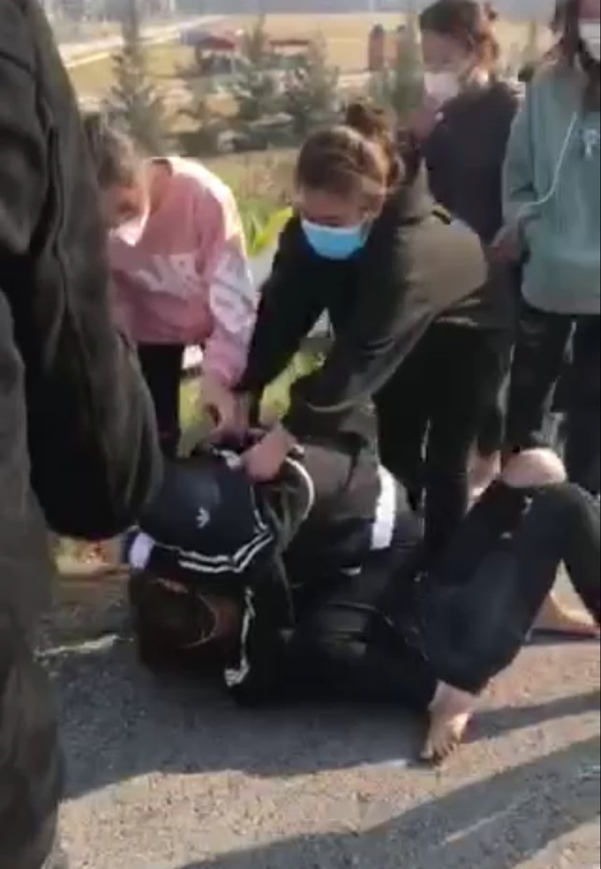  Cô gái mặc áo hồng liên tục dùng mũ bảo hiểm đập vào đầu đối phương khi đã bị đè xuống đất. Ảnh cắt từ clip