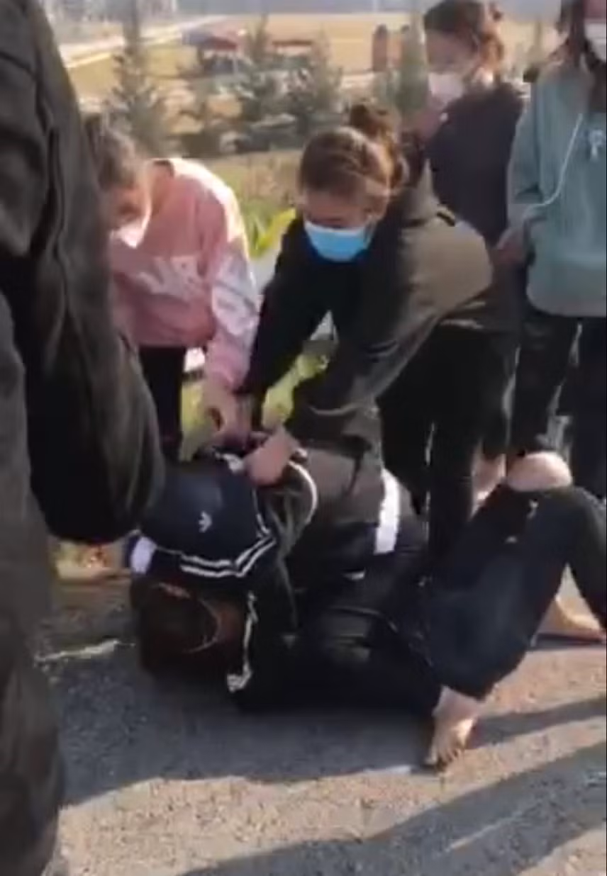  Cô gái mặc áo hồng liên tục dùng mũ bảo hiểm đập vào đầu đối phương khi đã bị đè xuống đất. Ảnh cắt từ clip