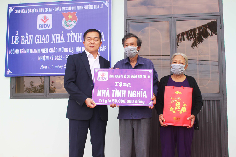 Đại diện Công đoàn Ngân hàng Thương mại cổ phần Đầu tư và Phát triển Việt Nam chi nhánh Gia Lai tặng bảng tượng trưng nhà tình nghĩa cho ông Đặng Phước Minh (ở giữa). Ảnh: Phan Lài