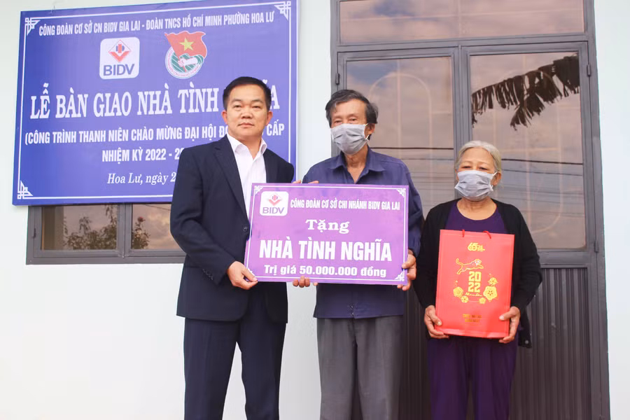 Đại diện Công đoàn Ngân hàng Thương mại cổ phần Đầu tư và Phát triển Việt Nam chi nhánh Gia Lai tặng bảng tượng trưng nhà tình nghĩa cho ông Đặng Phước Minh (ở giữa). Ảnh: Phan Lài