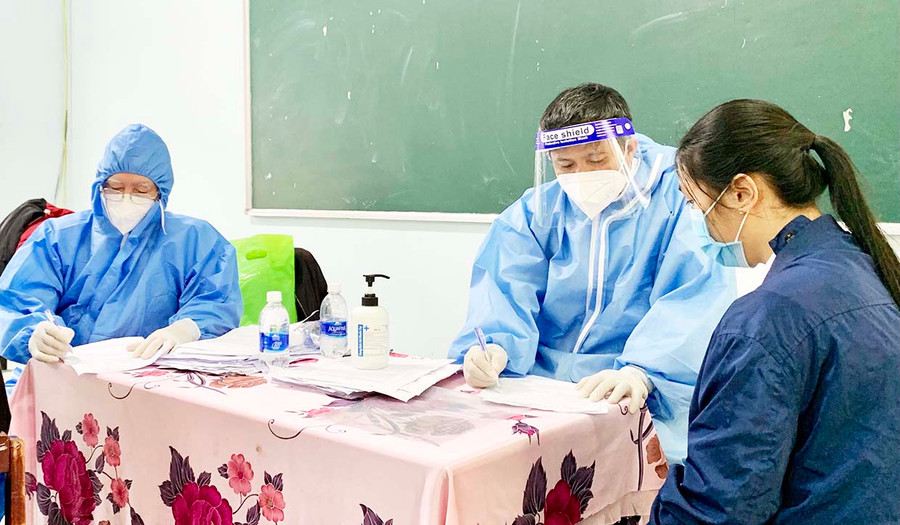  Nhân viên y tế khám sàng lọc trước khi tiêm vắc xin cho học sinh. Ảnh: Như Nguyện
