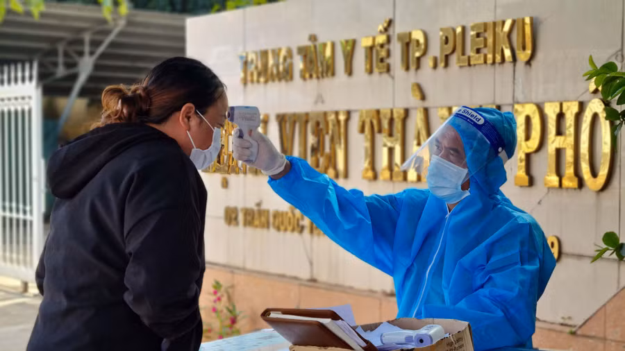 Nhân viên y tế kiểm tra thân nhiệt người dân trước khi vào Bệnh viện TP. Pleiku. Ảnh: Bá Bính