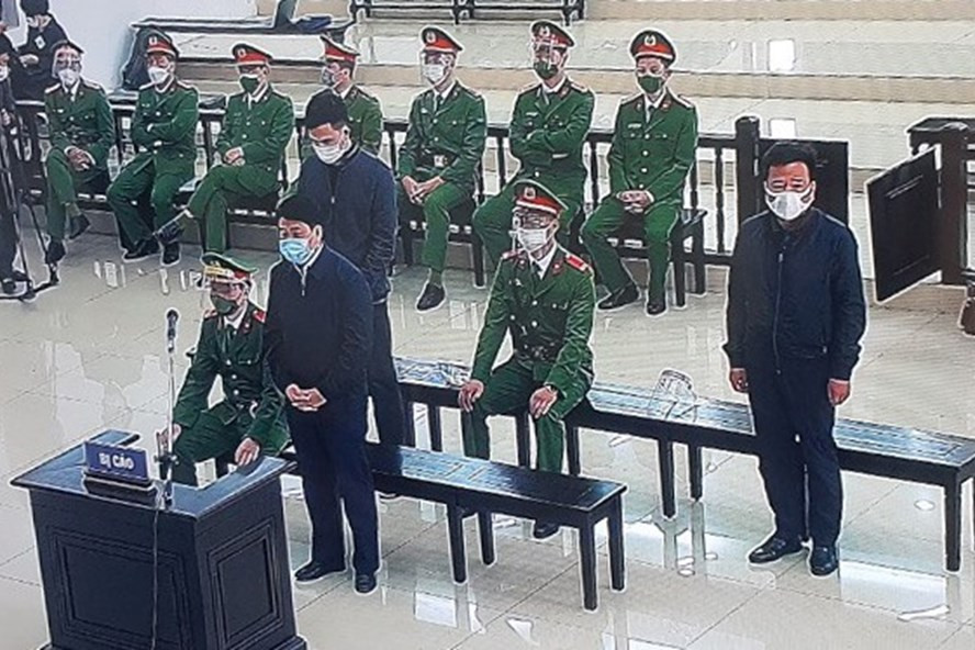 Ông Nguyễn Đức Chung (đứng đầu) cùng hai bị cáo nghe toà tuyên án. Ảnh chụp qua màn hình. Ông Nguyễn Đức Chung (đứng đầu) cùng hai bị cáo nghe toà tuyên án. Ảnh chụp qua màn hình.