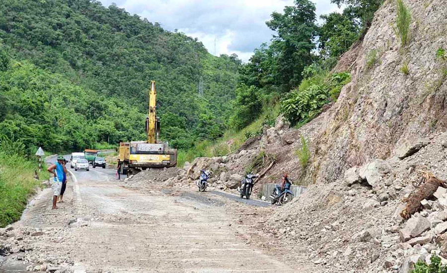 Đơn vị thi công đang dọn dẹp khối đất đá sạt lở tràn xuống mặt đường tại đèo Tô Na do cơn bão số 9. Ảnh: Lê Hòa
