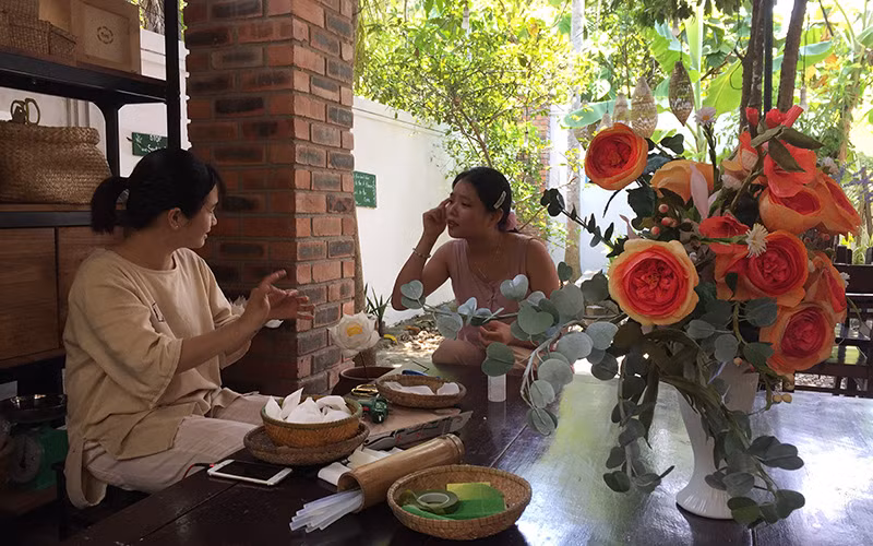 Lê Thị Thanh Nhàn (bên phải) cùng làm hoa giấy với cộng sự là người khuyết tật.