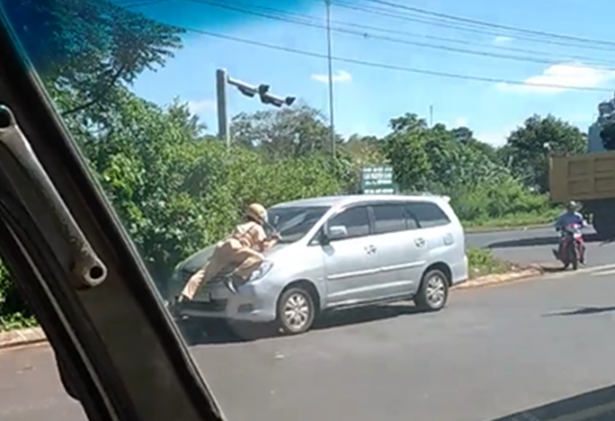 Một CSGT thuộc tổ công tác của Đội CSGT TP Buôn Ma Thuột (Đắk Lắk) lao ra chặn và đu mình trên nắp ca-pô để yêu cầu tài xế ôtô vi phạm dừng xe (ảnh từ clip)