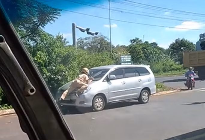 Một CSGT thuộc tổ công tác của Đội CSGT TP Buôn Ma Thuột (Đắk Lắk) lao ra chặn và đu mình trên nắp ca-pô để yêu cầu tài xế ôtô vi phạm dừng xe (ảnh từ clip)