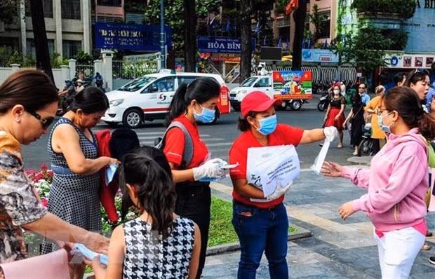 Nhân viên Sở Du lịch Thành phố Hồ Chí Minh phát khẩu trang miễn phí cho khách du lịch. (Ảnh: Đinh Hằng/TTXVN)