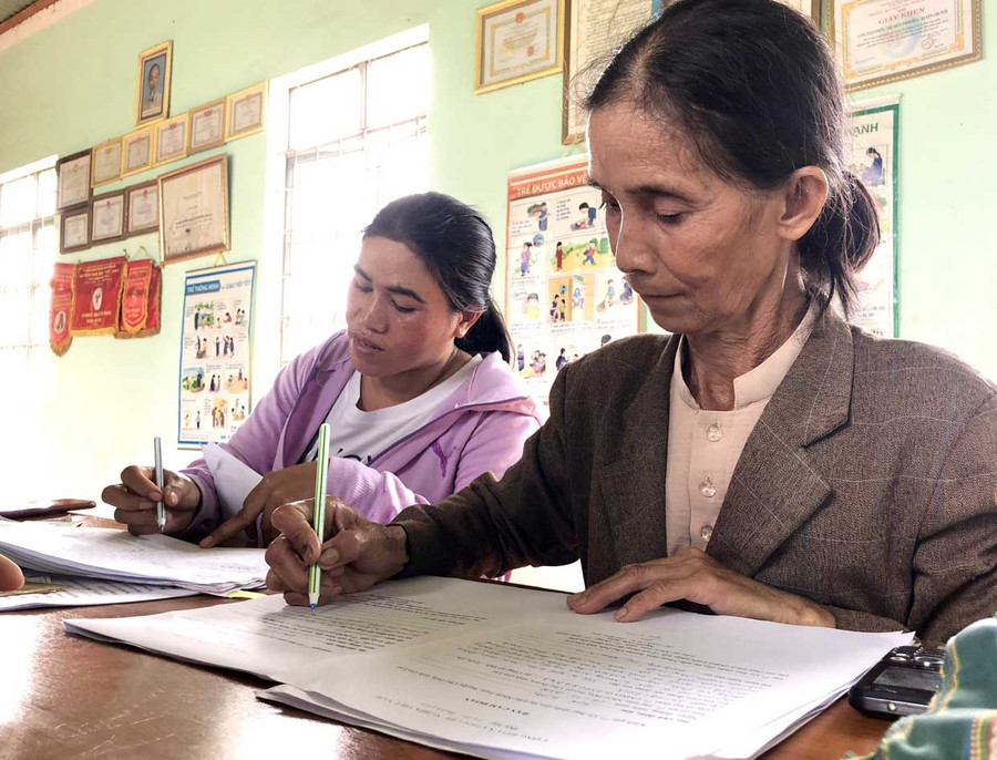 Bà Kpă H’Mi (bìa phải) giúp cán bộ Tư pháp thị trấn Nhơn Hòa, huyện Chư Pưh làm lại giấy khai sinh cho người dân. Ảnh: TRẦN DUNG