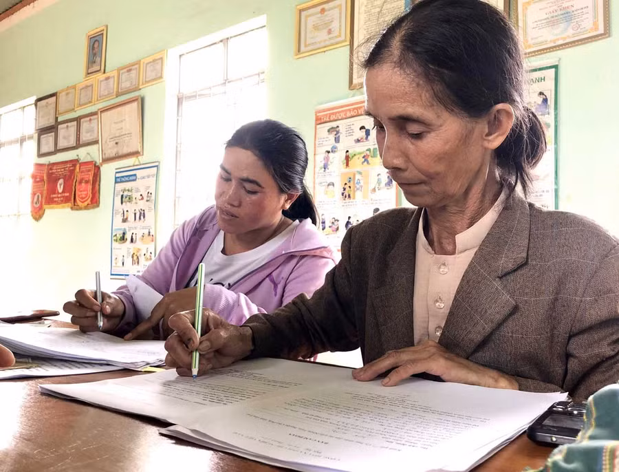 Bà Kpă H’Mi (bìa phải) giúp cán bộ Tư pháp thị trấn Nhơn Hòa, huyện Chư Pưh làm lại giấy khai sinh cho người dân. Ảnh: TRẦN DUNG