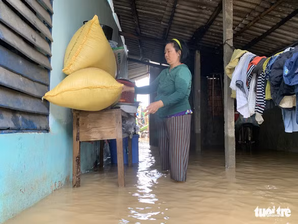 Người dân dầm mưa lũ, kê tài sản lên cao, chuẩn bị rời khỏi nhà nếu lũ tiếp tục lên cao - Ảnh: T.M.