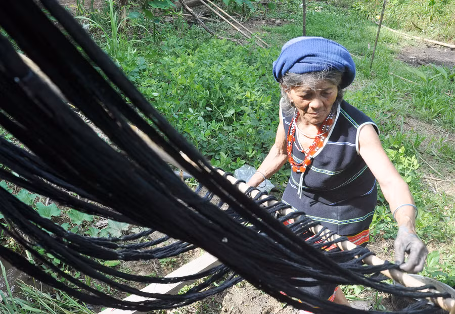 Nghệ nhân dệt thổ cẩm với đôi tay “nhuốm chàm”. Ảnh: Tấn Vịnh