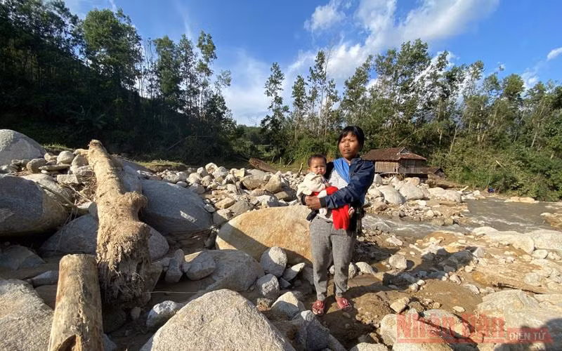 Đinh Thị Điền đứng trên nên nhà của mình. Lũ cuống phăng nền ngôi nhà của gia đình bảy người thân của Điền giờ chỉ còn là những tảng đá ngổn ngang trên núi cao đổ xuống. 