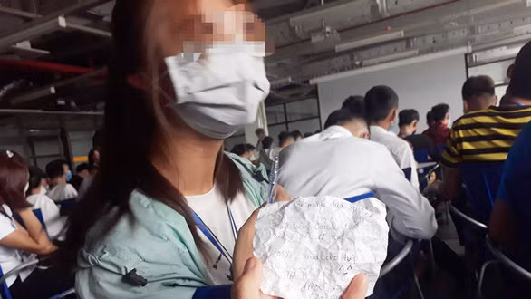 Lá thư viết tay vo cuộn được công nhân trẻ chuyển cho nhau nơi làm việc - Ảnh: TÂM LÊ