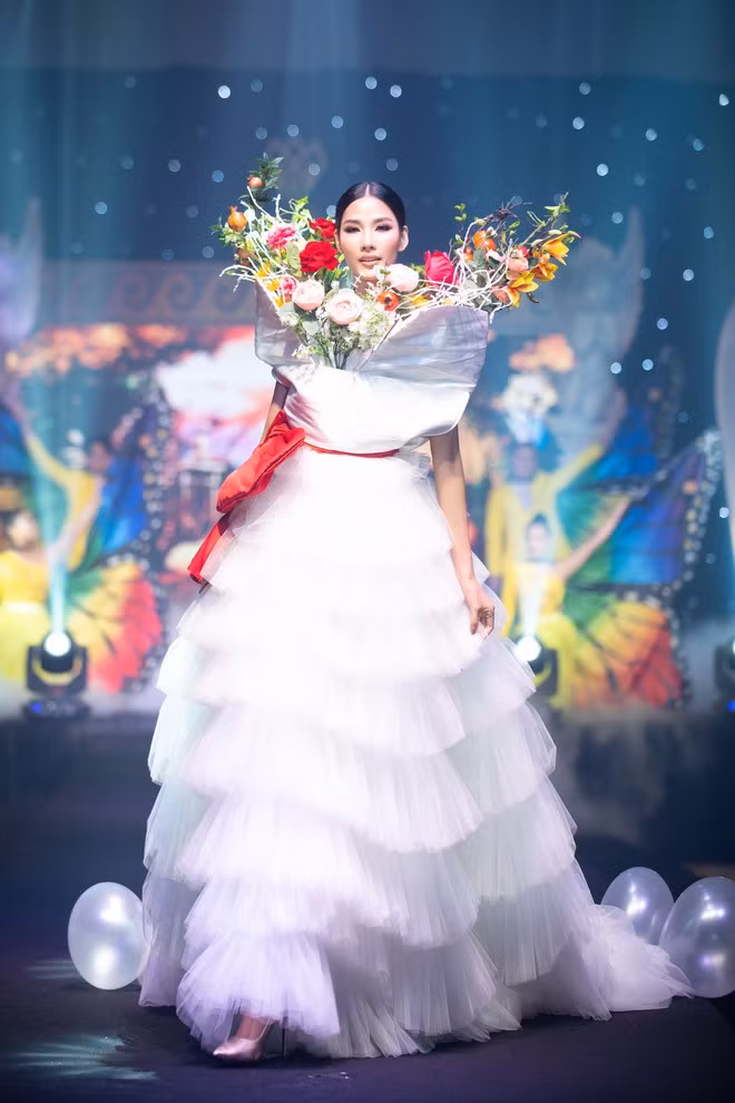 Đối lập với hình ảnh sắc sảo của Lan Khuê, Á hậu Hoàng Thùy diện một thiết kế đầm xòe xếp nhiều tầng màu trắng. Phần hoa lá đủ màu sắc đính ở phần cổ giúp tổng thể trở nên ấn tượng hơn. ẢNH: NGUYỄN XUÂN HUY