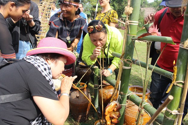  Người lớn trải nghiệm uống rượu cần của người Bana, mỗi người lại có một cảm nhận riêng về mức độ 'nặng đô' của loại rượu. (Ảnh: Minh Anh/Vietnam+)